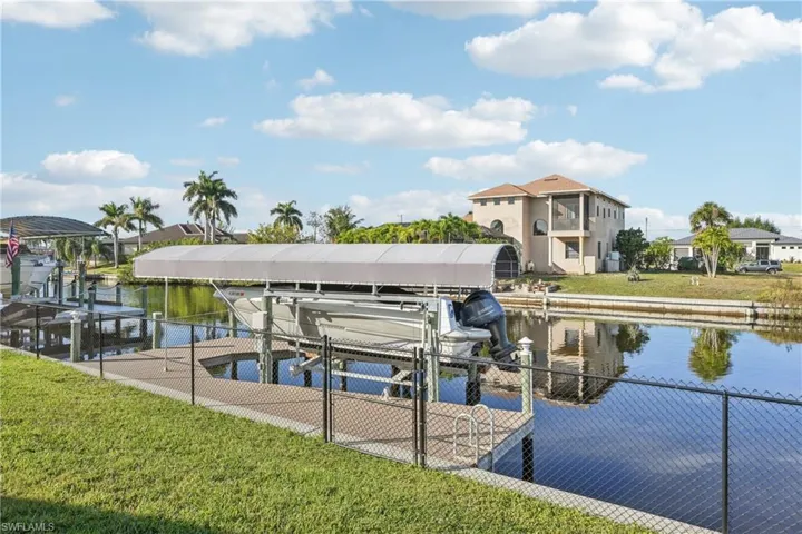 Dock with a lawn, boat lift, and a water view