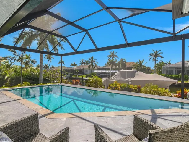 Outdoor pool featuring a patio area, glass enclosure, and a residential view