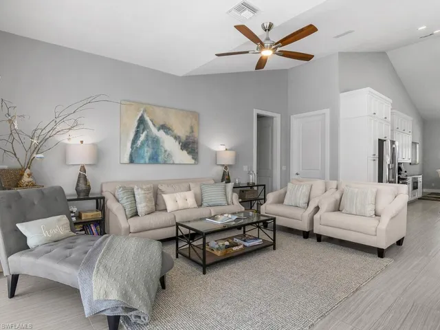 Living room with lofted ceiling, ceiling fan, light wood-style floors, and recessed lighting