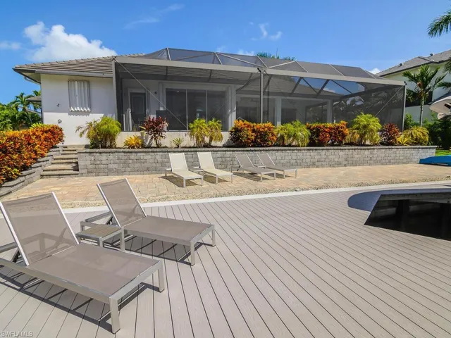 Back of house with stucco siding, a lanai, and a deck