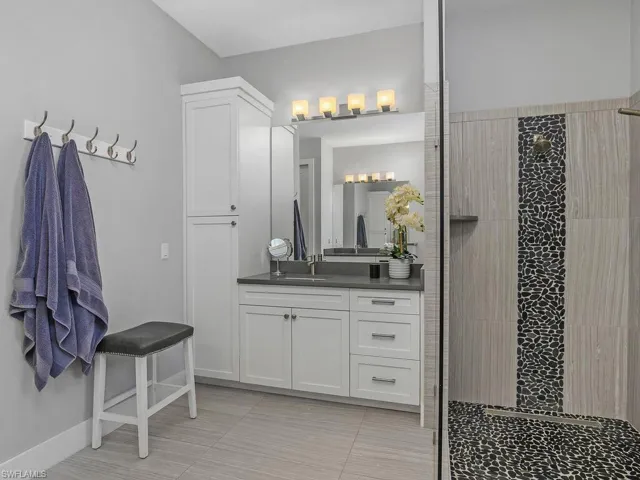 Bathroom with vanity, a tile shower, and tile patterned floors