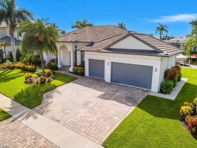 View of front of home featuring a front yard, decorative driveway, a garage, and stucco siding