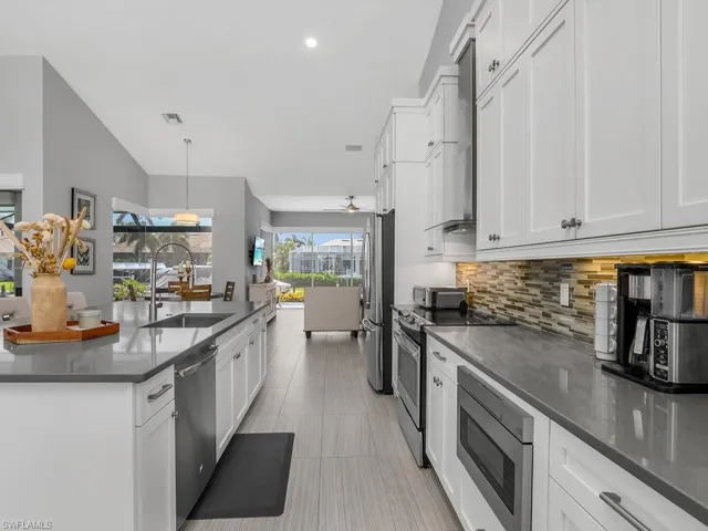 Kitchen with appliances with stainless steel finishes, decorative backsplash, white cabinetry, ceiling fan, and recessed lighting