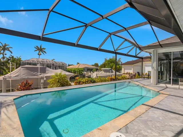 Swimming pool with a patio, glass enclosure, and a residential view