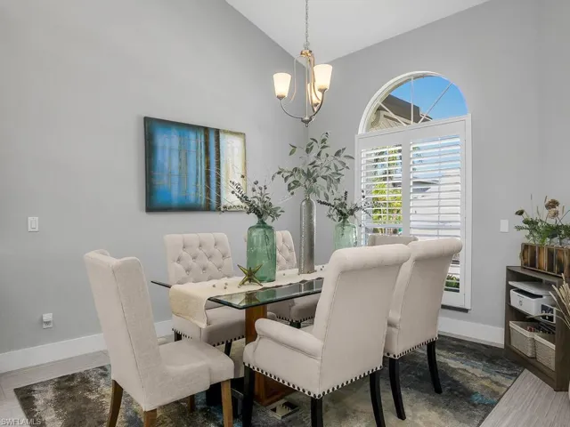 Dining space with a chandelier, wood finished floors, and high vaulted ceiling
