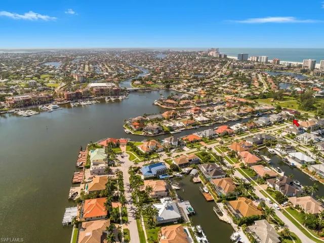 Aerial view of property and surrounding area featuring a nearby body of water and nearby suburban area