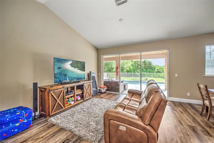 Living room with lofted ceiling, plenty of natural light, and wood-type flooring