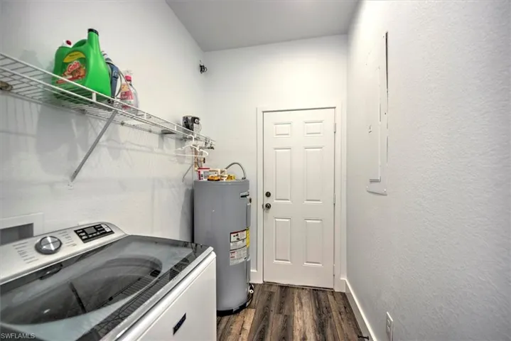 Laundry room featuring washer / clothes dryer, dark hardwood / wood-style floors, and electric water heater