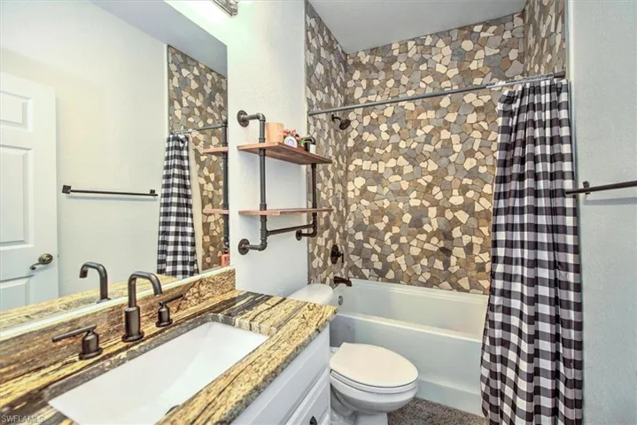 Full bathroom with shower / bath combination with curtain, vanity, and toilet