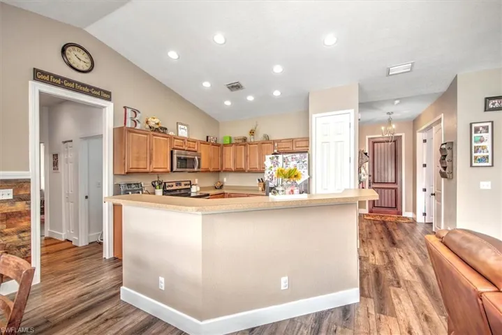 Kitchen with appliances with stainless steel finishes, a kitchen island, and wood-type flooring