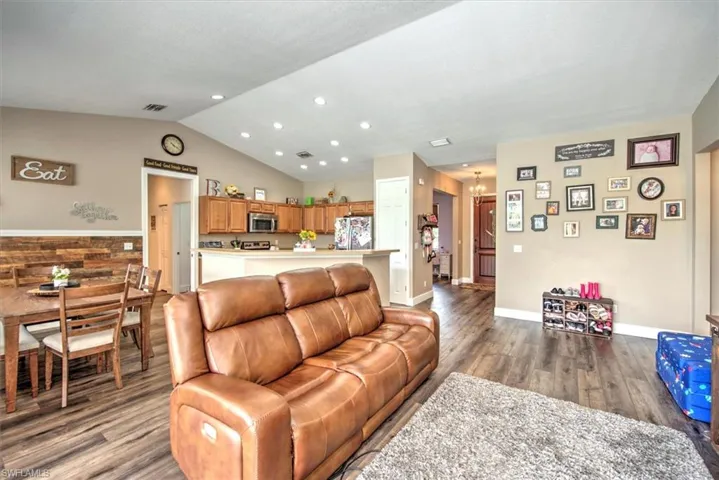 Living room featuring a notable chandelier, hardwood / wood-style flooring, and vaulted ceiling