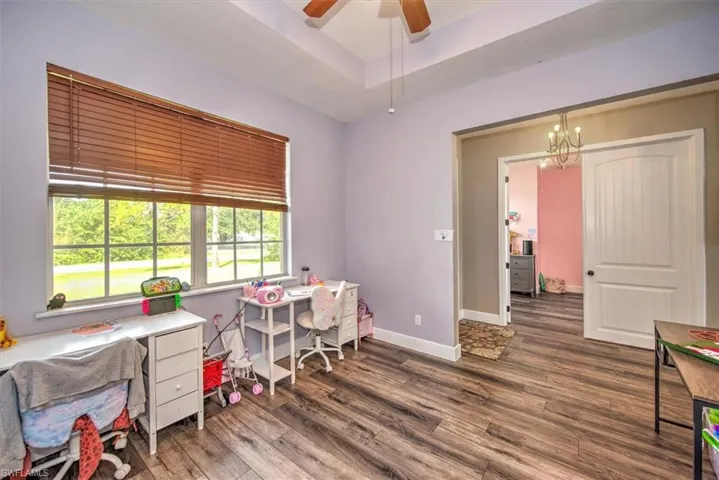 Office space with a raised ceiling, dark hardwood / wood-style flooring, and ceiling fan