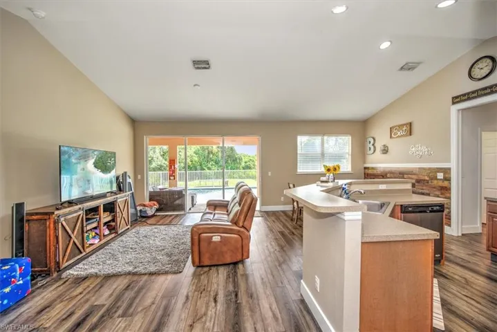 Kitchen featuring dishwasher, a center island with sink, vaulted ceiling, and a healthy amount of sunlight