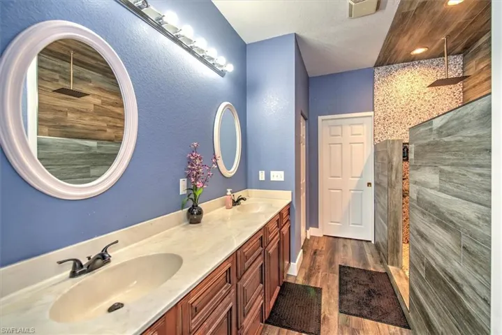 Bathroom featuring vanity, hardwood / wood-style floors, a tile shower, and a textured ceiling
