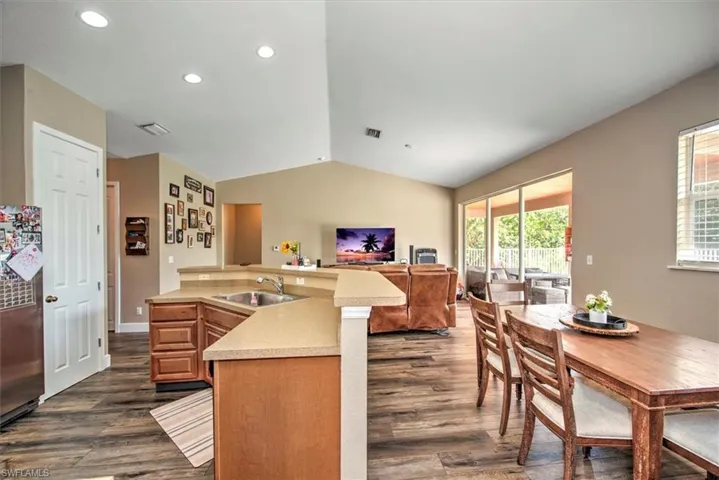 Kitchen with stainless steel fridge, dark hardwood / wood-style floors, vaulted ceiling, and sink