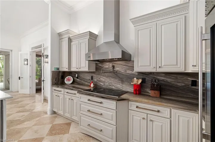 Kitchen with custom hardwood cabinets, custom countertops and backsplash, and Wolf commercial grade cooktop, Viking custom exhaust hood