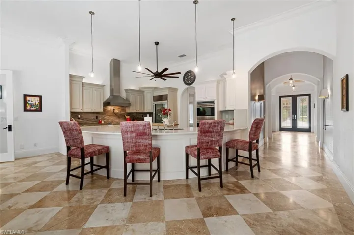 Kitchen with pendant lighting, a breakfast bar, and hallway leading to glass front entry doors