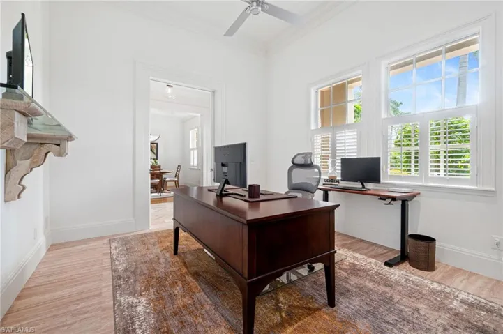 Office with cork impact resistant flooring, double glass pocket French doors, ceiling fan, and crown molding