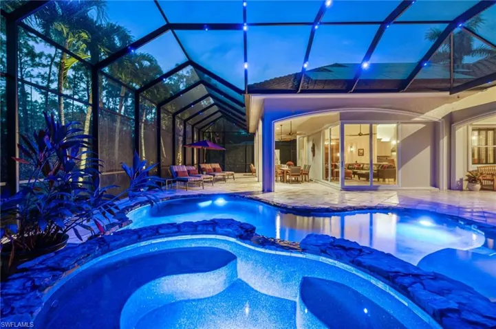 View of pool at dusk w/ Nebula lighting in blue, an in-ground spa, and an expansive patio area
