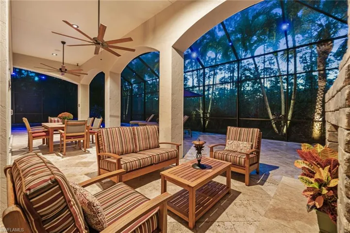 View of patio at dusk with an outdoor cobblestone gas fireplace and ceiling fan