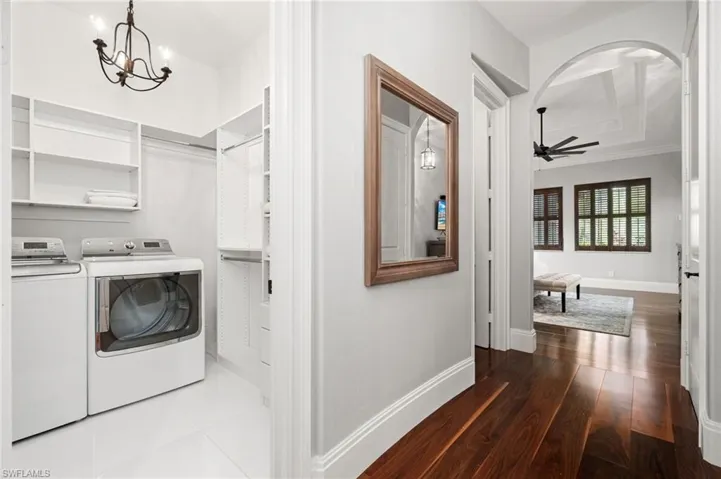One of two laundry rooms in home, this is in Primary ensuite featuring a chandelier, washing machine and dryer