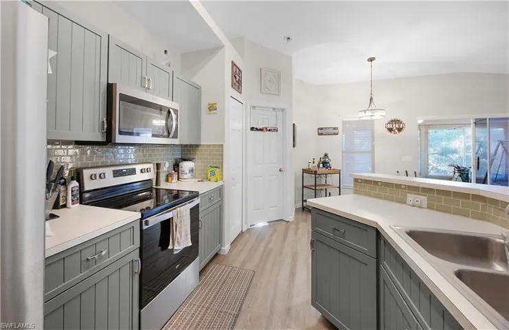 Kitchen featuring stainless steel appliances, light countertops, decorative backsplash, and a peninsula