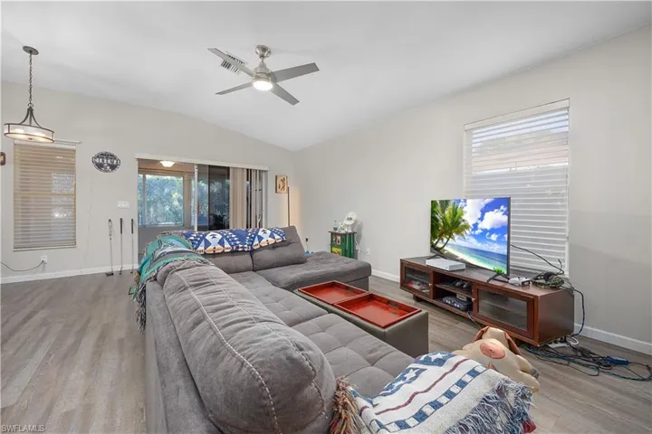 Living room featuring wood finished floors, a ceiling fan, and vaulted ceiling