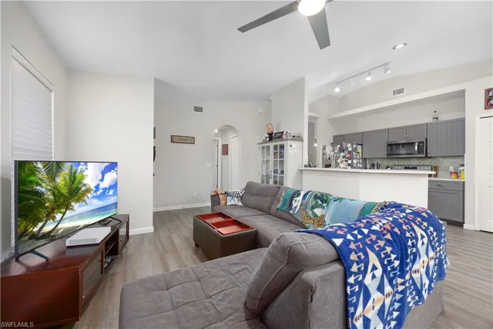 Living room with light wood finished floors, healthy amount of natural light, ceiling fan, and lofted ceiling