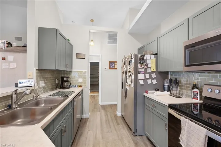 Kitchen featuring gray cabinetry, stainless steel appliances, a peninsula, light countertops, and tasteful backsplash