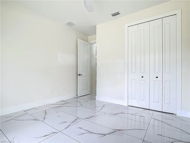 Unfurnished bedroom featuring a closet, light marble finish flooring, and a ceiling fan