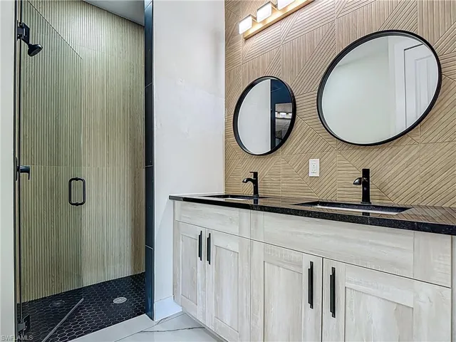 Full bath featuring a stall shower and double vanity