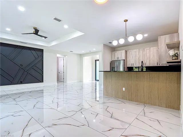Kitchen featuring stainless steel fridge with ice dispenser, open floor plan, a ceiling fan, light brown cabinets, and recessed lighting