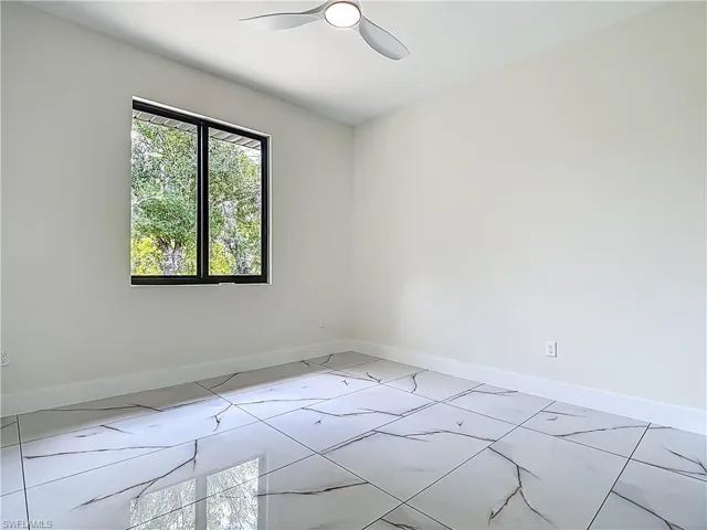 Unfurnished room with ceiling fan and light marble finish flooring