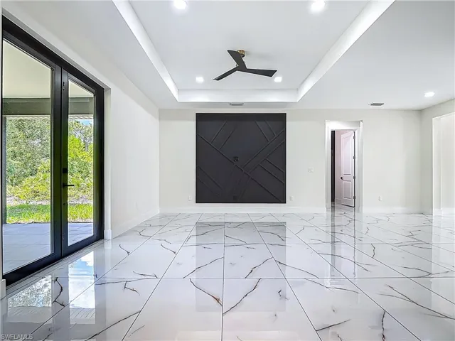 Empty room featuring light marble finish flooring, recessed lighting, custom feature wall, a raised ceiling, and a ceiling fan