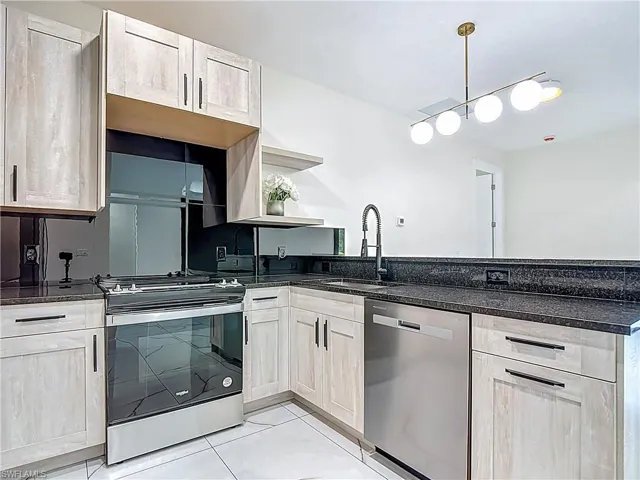 Kitchen featuring stainless steel appliances, open shelves, light tile patterned flooring, a peninsula, and dark stone countertops