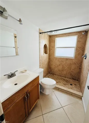 Full bathroom featuring a walk-in shower with diagonal tilework, a built-in shower niche, and a window