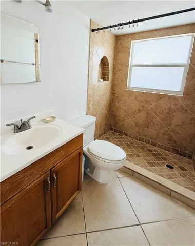Tiled shower enclosure featuring an integrated wall niche, a privacy window, and a dark-finish shower curtain rod