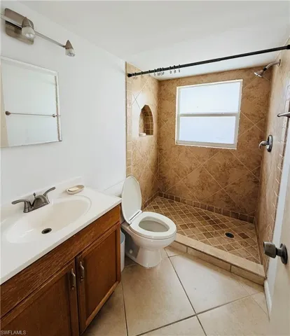 Full bathroom featuring a walk-in shower with tile surround, built-in niche, and window