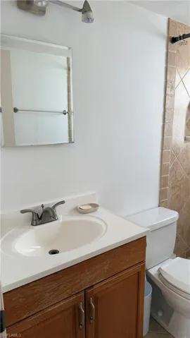 Bathroom vanity with integrated sink, white countertop, and wood-finish cabinetry