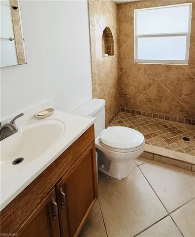 Tiled shower with an arched niche and a frosted window