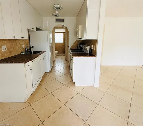 Kitchen featuring white cabinetry, brown flecked countertops, and a tiled backsplash