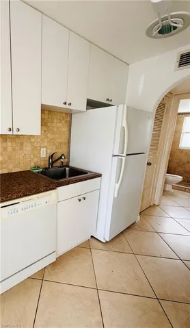 Kitchen area featuring white upper and lower cabinetry, a double basin sink, and a brown speckled countertop