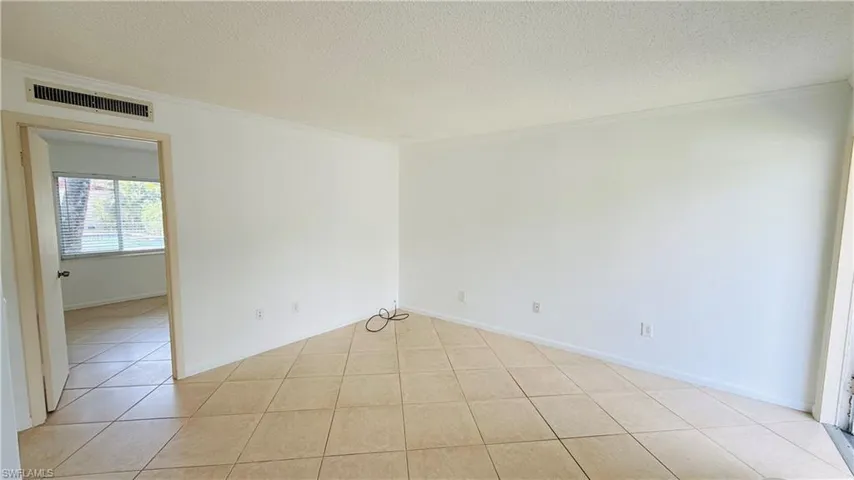 Neutral-toned ceramic tile flooring extends throughout this expansive interior, featuring white walls and crown molding