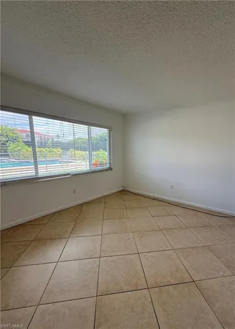 Spacious room featuring neutral tile flooring and a textured ceiling