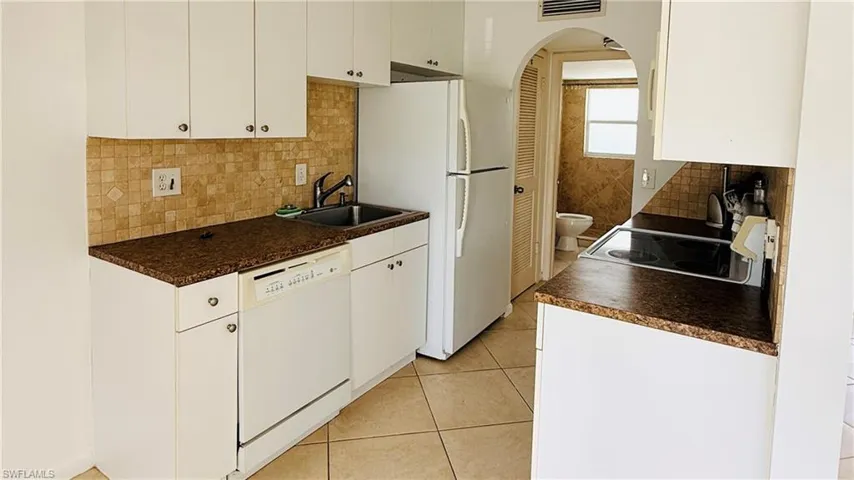 Kitchen featuring white cabinetry, brown speckled countertops, and a mosaic tile backsplash