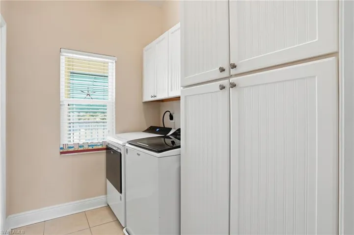 Laundry room with cabinet space, light tile patterned floors, and separate washer and dryer