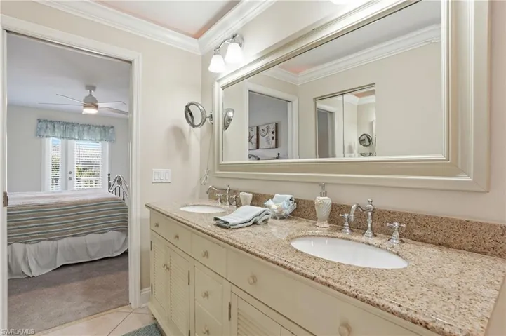 Bathroom featuring ensuite bathroom, double vanity, crown molding, light tile patterned floors, and light carpet