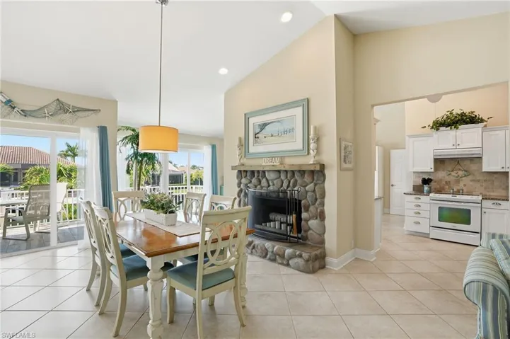 Dining area featuring light tile patterned flooring, lofted ceiling, a stone fireplace, and recessed lighting