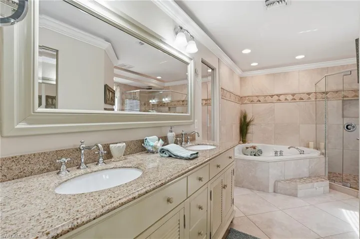 Bathroom with a shower stall, double vanity, a garden tub, ornamental molding, and light tile patterned floors