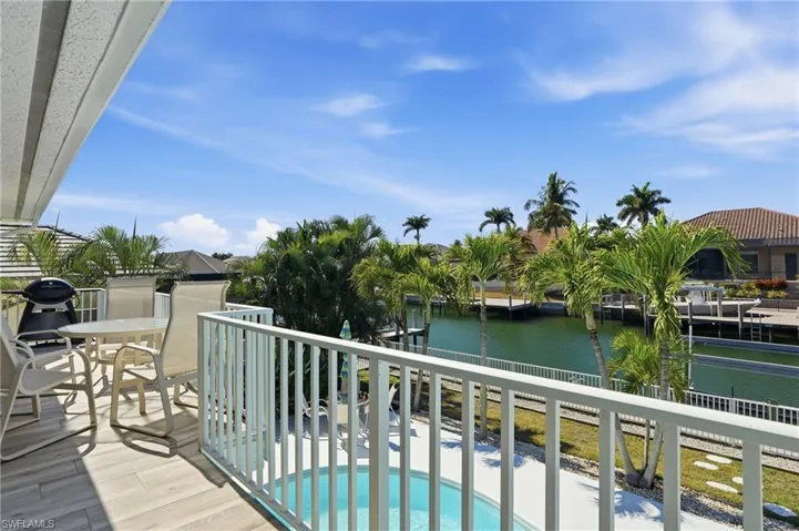 Balcony with a water view, view of pool, and grilling area